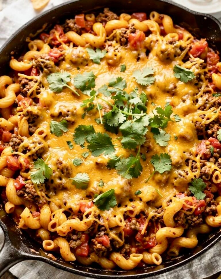 A creamy one-pan taco pasta skillet topped with melted cheese and fresh cilantro.